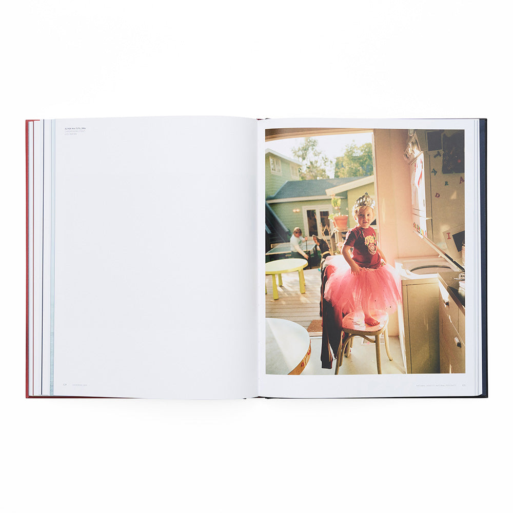 Open book showing a photograph of a child in a pink dress standing on a chair.