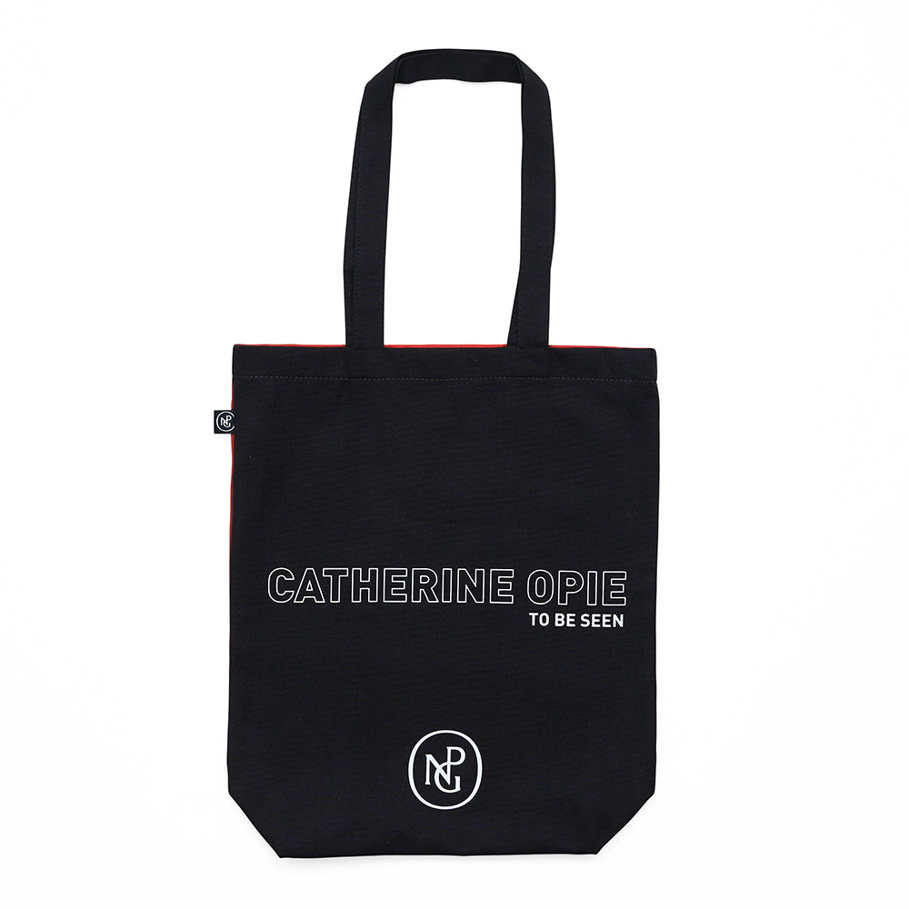 Reverse of tote bag with 'catherine opie to be seen' text against black on a white background