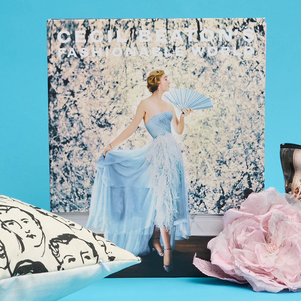 Book cover with a woman in a blue dress against a floral background, surrounded by decorative floral brooch and illustrated cushion against a blue background.