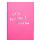 A4 rectangular scrapbook in pink with the worlds 'Cecil Beaton's Scrapbook' in silver foil in a handwritten style