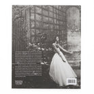 Back book cover featuring a black and white photograph of a woman in a white dress standing against a garden backdrop.