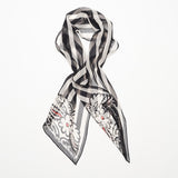 Styled long black and white striped silk scarf with floral motif.