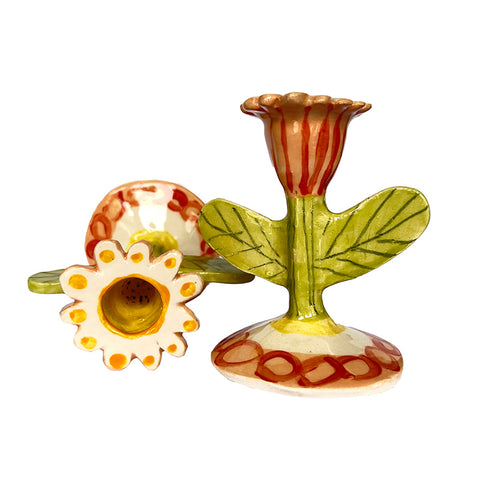 A pair of flower candlestick holders, one upright, one tipped over, showing the opening of the holder.