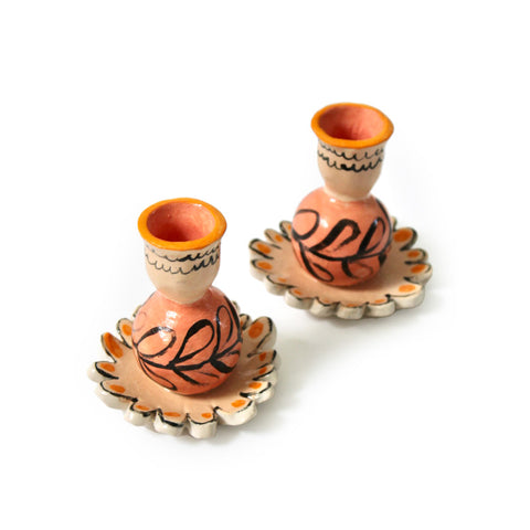 Hand-painted candlestick holders with a flower base and a round holder on top.