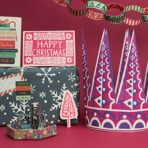 One pink and purple Christmas crown with a wrapped present, a Happy Christmas card and some other Christmas trinkets. 