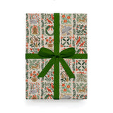 Christmas wrapping paper with colourful red and green garlands and objects, with a big green bow. 