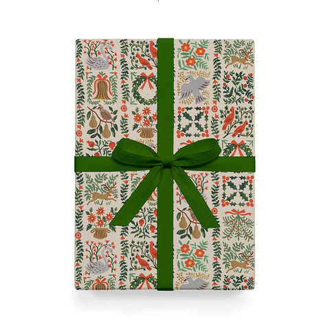 Christmas wrapping paper with colourful red and green garlands and objects, with a big green bow. 