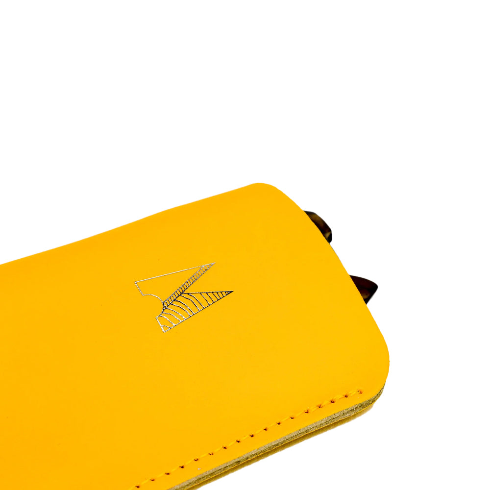 Detail close up of a yellow leather glasses case with logo and stitching.
