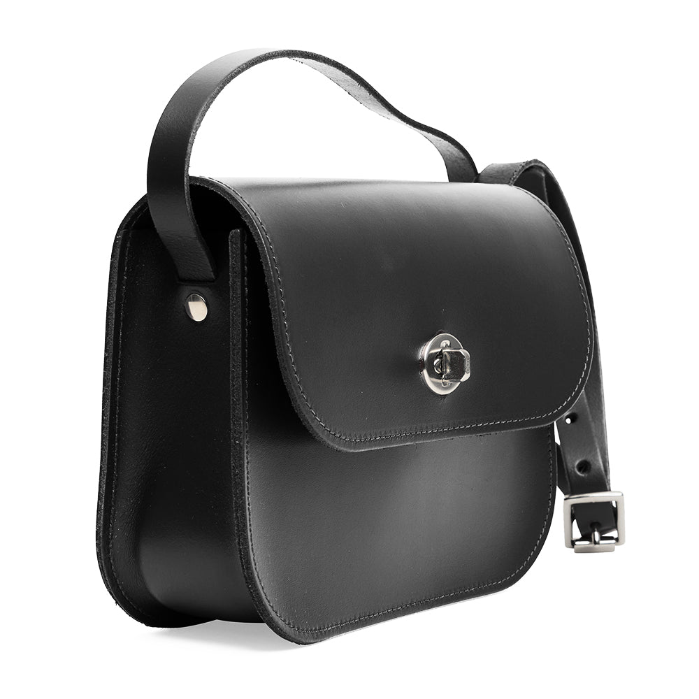 Black leather handbag with a strap and silver clasp on a white background