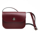 Maroon leather handbag with a strap on a white background