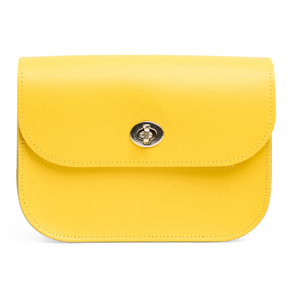 Yellow leather handbag with a silver clasp on a white background