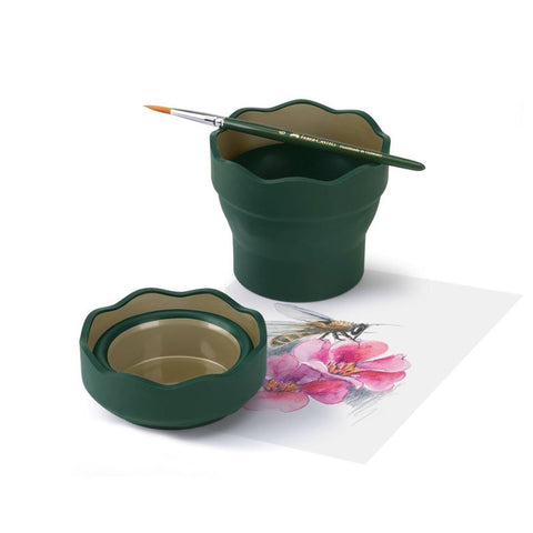 A green paintbrush cup with balanced paintbrush on top, below is a painting of a bee on a flower.