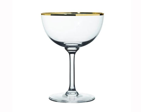 A glass champagne coupe glass with a gold rim. 