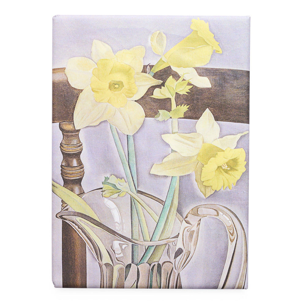 Magnet featuring a painting of daffodils in a glass jug on a wooden chair.