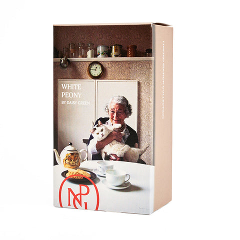 A box of tea featuring a photographic portrait of Judith Kerr at a breakfast table drinking tea and holding a cat.