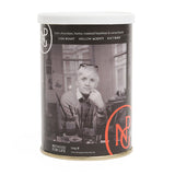 A metal coffee tin with white lid featuring a black and white photo of David Hockney in his studio. 