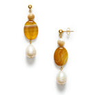 A pair of drop earrings with hanging gems of pearl and golden jade against a white background