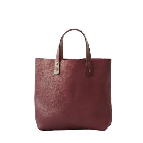 A brown tan leather square tote bag with short leather handles and copper rivets.