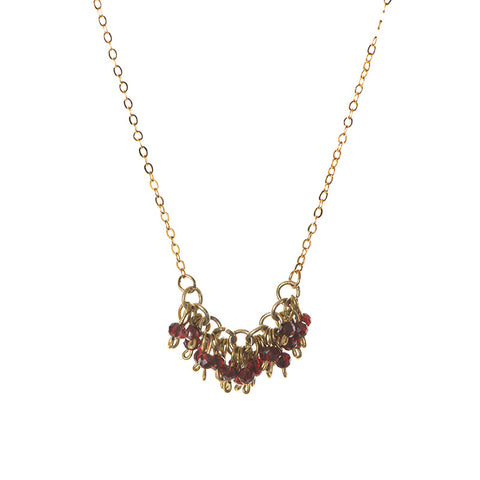 A cluster of red glass beads on gold hoops hang from a gold chain.