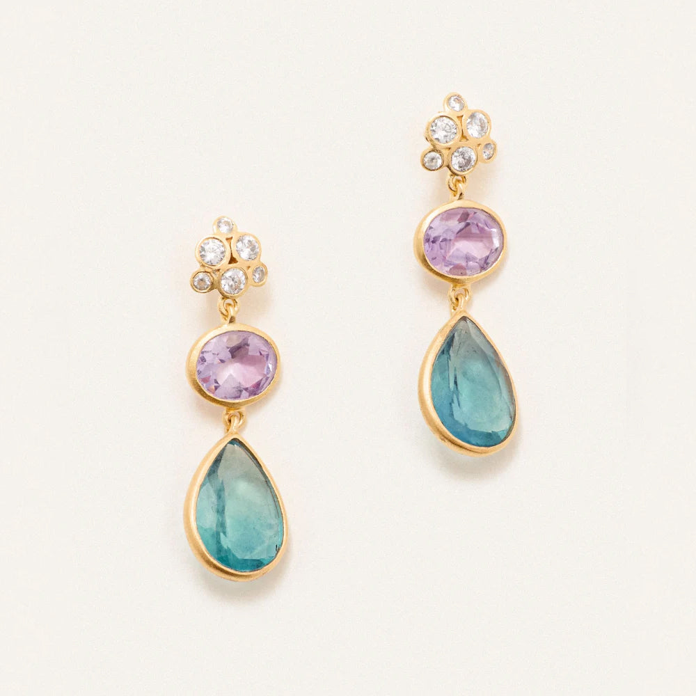 A pair of drop earrings with 5 silver crystals and 2 lower pink and blue crystals below against a cream background.