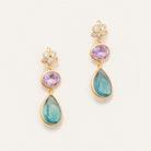 A pair of drop earrings with 5 silver crystals and 2 lower pink and blue crystals below against a cream background.