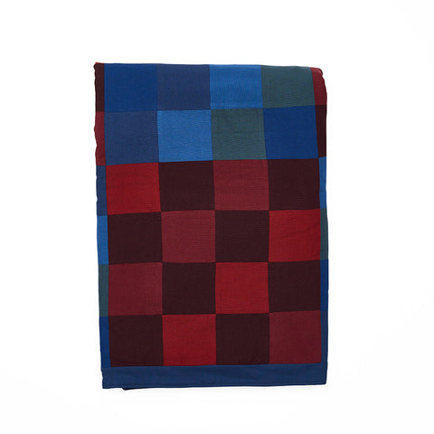 Folded chequered multicoloured blue, red and green quilted throw.