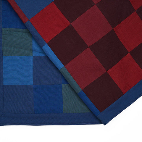 Close up of the large chequered multicoloured blue, red and green quilted throw.