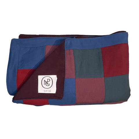 Neatly folded red and blue chequered throw blanket with one corner folded over to see the NPG logo.