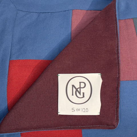 Detail of the NPG logo on the chequered red and blue quilted throw blanket.
