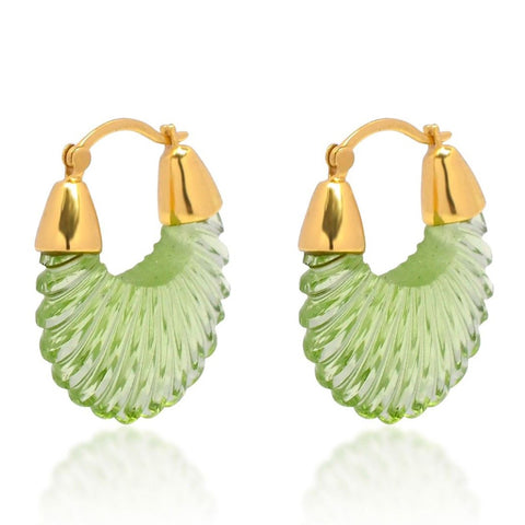 A pair of cut glass pendants in soft green colour hanging from gold hoop earrings.