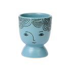 Blue ceramic cup with face design on a white background