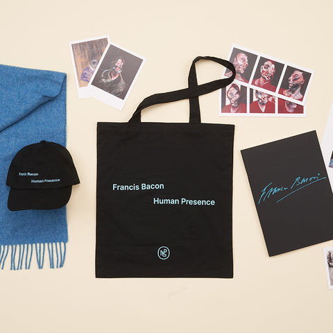 Collection of items, including the black tote bag, the black baseball hat, the black sketchbook, a blue wool scarf and several Francis Bacon postcards.