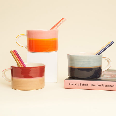 Three mugs in three toned colours with pencils sticking out. 