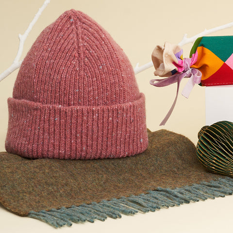 The dusty punk coloured hat, upright on a green scarf.