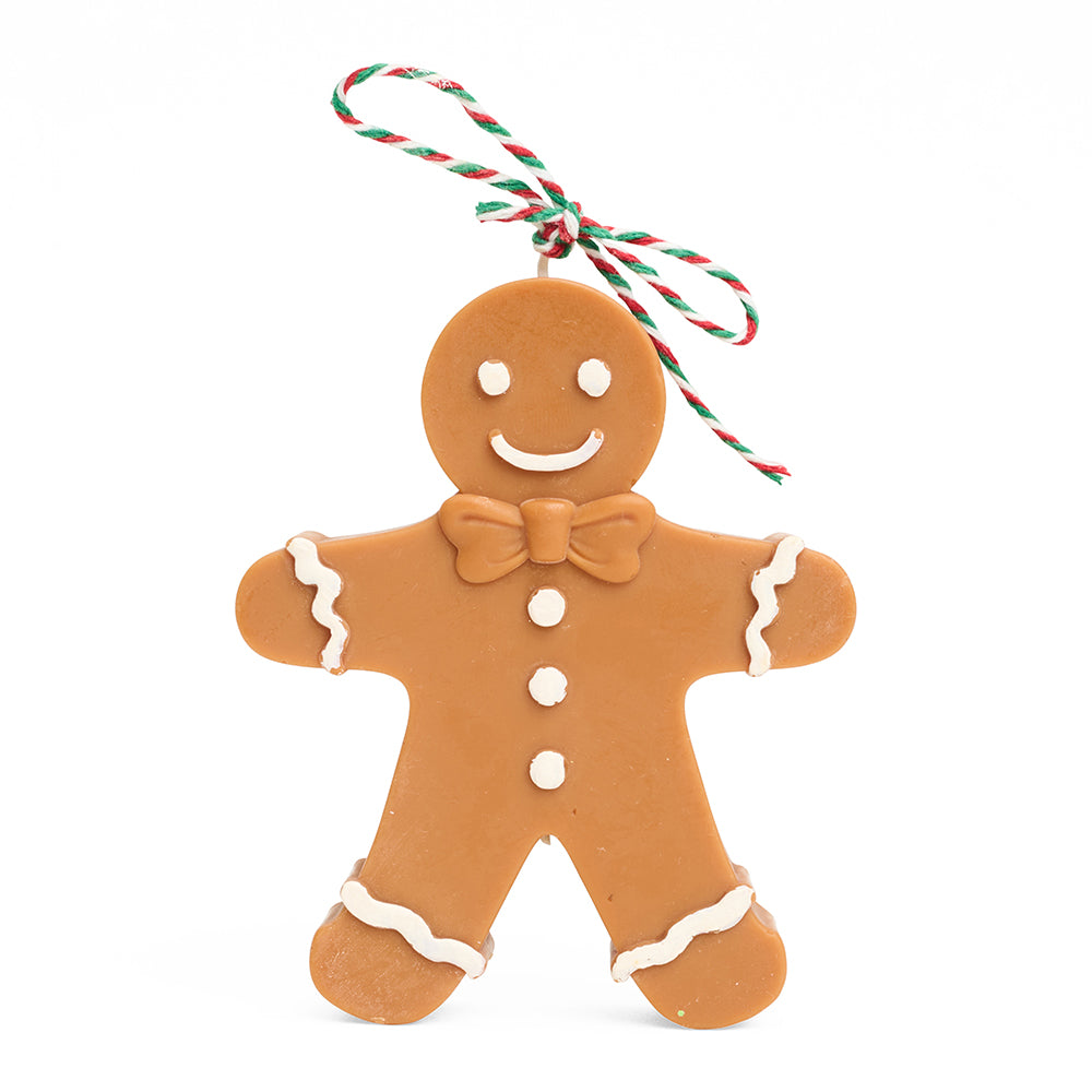Gingerbread man candle with icing details and a string bow against a white background.