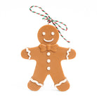 Gingerbread man candle with icing details and a string bow against a white background.