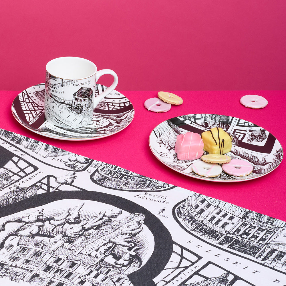 Cup and saucer with decorative map design on a pink background
