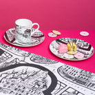 Cup and saucer with decorative map design on a pink background