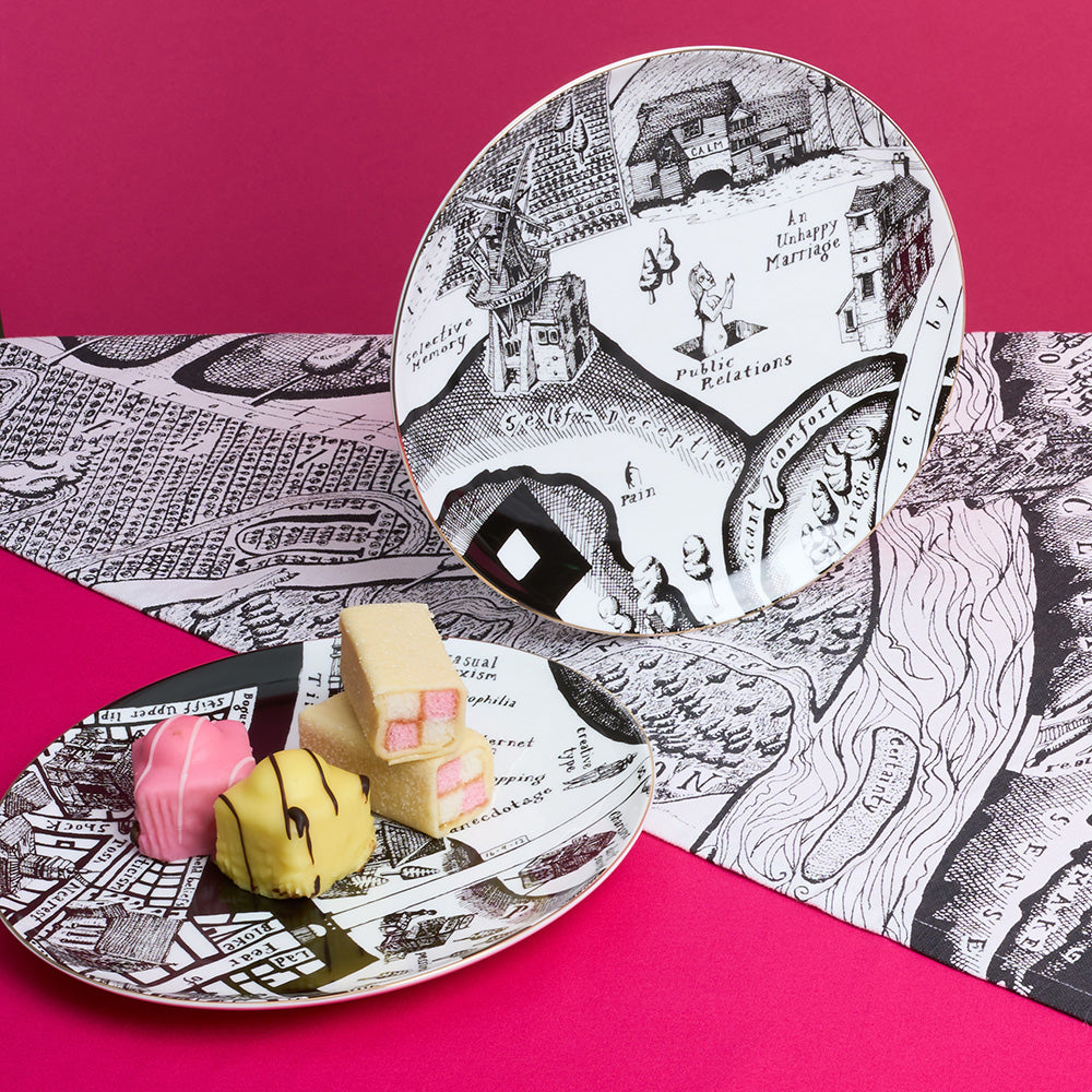 Decorative plates with black and white map illustrations on a pink background