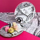 Decorative plates with black and white map illustrations on a pink background