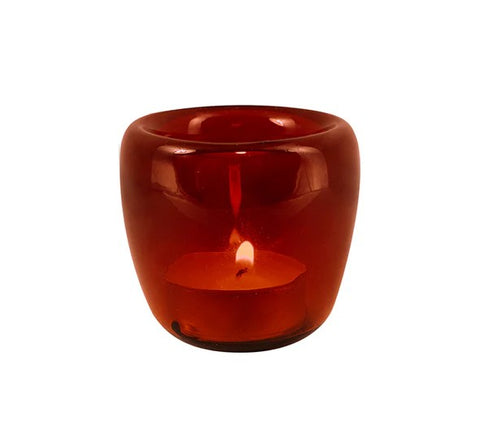 A red rounded glass tea light candle holder with lit candle inside.