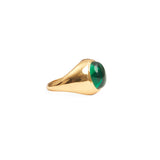 Side view of the chunky gold ring with a bright green stone. 