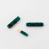 Green marbled fountain pen with lid and gold hardware in its separate pieces. 