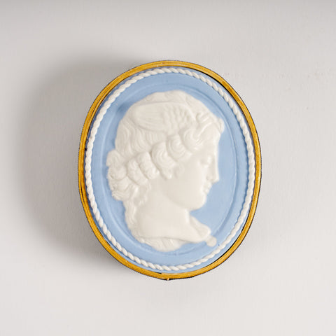 Oval paperweight in blue and white featuring a profile portrait of a woman's head. 