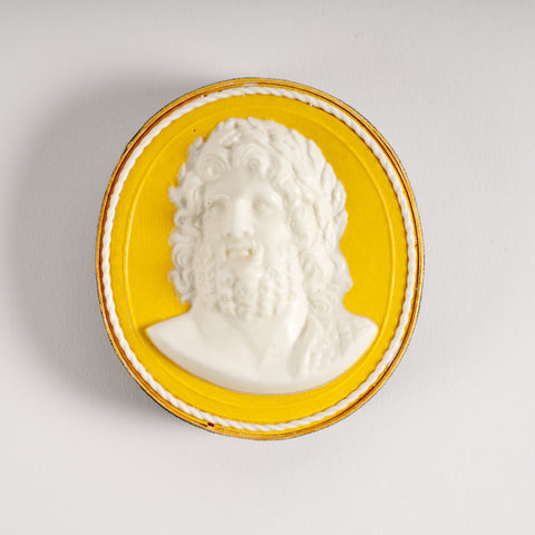 Oval paperweight in yellow and white featuring a portrait of bearded man.. 