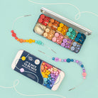 Colourful beading kit with beads and packaging on a light blue background