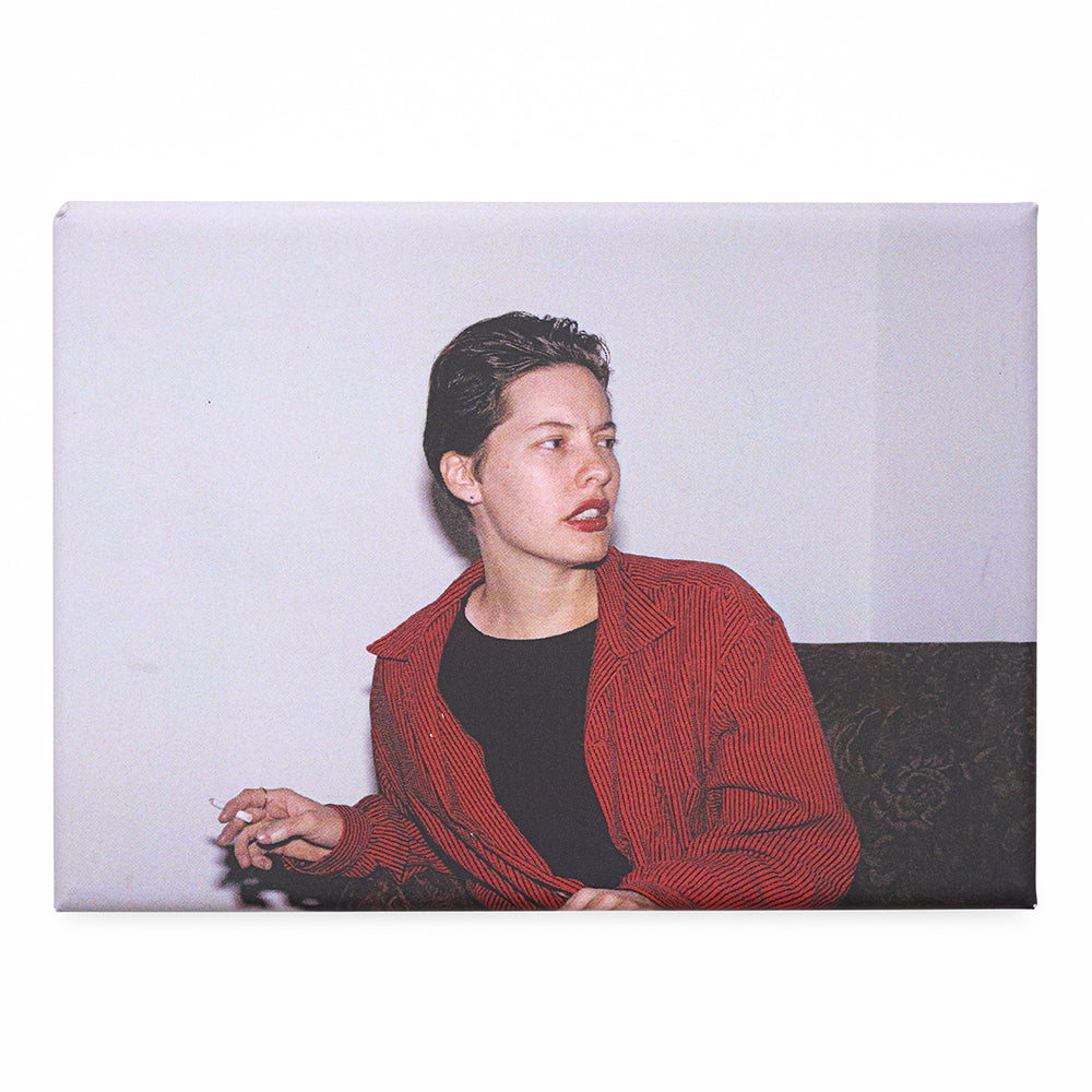 Magnet with a photograph of a person wearing a red jacket sitting on a couch with a white background