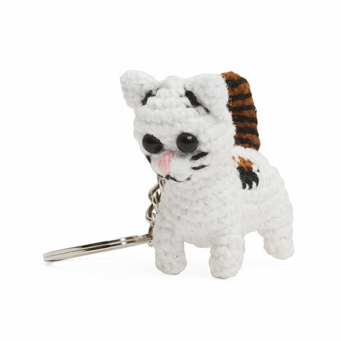 A white crochet cat with brown tail hangs from a silver keychain.