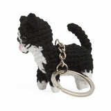 Side view of a black and white crochet cat on a silver keychain.