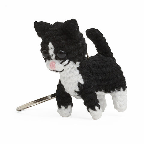 A black and white crochet cat with black beaded eyes on a silver keychain.